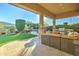 Covered backyard patio with an outdoor kitchen, comfortable seating, and a hot tub in the background at 4053 E Zion Way, Chandler, AZ 85249