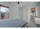 Bright bedroom featuring a large window with blinds, a bed with stripped bedding, and sliding closet doors at 4053 E Zion Way, Chandler, AZ 85249