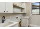 Well-lit laundry room featuring white cabinets, open shelving, quartz countertops, and modern fixtures at 4420 E Glenrosa Ave, Phoenix, AZ 85018