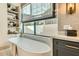 Luxurious bathroom featuring a soaking tub under a window and gray cabinets with marble countertops at 8334 E Jenan Dr, Scottsdale, AZ 85260