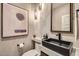 Stylish half-bathroom with unique sink, marble wall, and modern lighting at 8334 E Jenan Dr, Scottsdale, AZ 85260