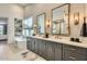 Bright bathroom featuring a double vanity with gray cabinets, freestanding tub, and large mirrors at 8334 E Jenan Dr, Scottsdale, AZ 85260