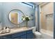 Elegant bathroom with a blue vanity, a large mirror, and a modern soaking tub at 11748 N 80Th Pl, Scottsdale, AZ 85260