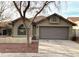 Tan one-story house with a brown garage door and a tree in the front yard at 10240 N 65Th Ln, Glendale, AZ 85302