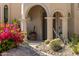 Charming front entrance featuring arched columns, desert flora, and blooming bougainvillea at 10420 E Morning Vista Ln, Scottsdale, AZ 85262