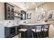 Stylish wet bar with dark cabinetry, pendant lighting, open shelving, and beverage cooler at 10922 E Purple Aster Way, Scottsdale, AZ 85262