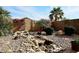 Lush backyard with a calming water feature, mature trees, and a decorative rock landscape at 14767 N 148Th Ave, Surprise, AZ 85379