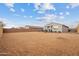 Large sandy backyard with a view of the house and neighboring homes at 4887 N 179Th Dr, Goodyear, AZ 85395