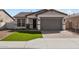 Charming single-story home with a well-manicured lawn, a paver driveway, and a gray-painted two car garage at 5525 N 193Rd Dr, Litchfield Park, AZ 85340