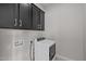This laundry room has upper cabinets and modern, front-loading washing machine at 5525 N 193Rd Dr, Litchfield Park, AZ 85340