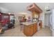 Open kitchen with a breakfast bar, wood cabinets, and an adjacent living space at 9821 W Cedar Dr, Sun City, AZ 85351