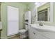 White bathroom vanity with sink and toilet, with light green walls and a shower at 10631 W Brookside Dr, Sun City, AZ 85351