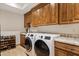 Laundry room with modern washer, dryer and wood cabinets at 14179 E Kalil Dr, Scottsdale, AZ 85259