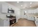 Modern kitchen with white cabinets, stainless steel appliances, and light wood floors at 1743 W Verde Ln, Phoenix, AZ 85015