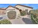 Tan colored house with a two-car garage and desert landscaping at 18489 N Davis Dr, Maricopa, AZ 85138