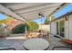 A covered back patio with lounge seating surrounded by lush foliage and a serene backyard at 1632 E Maryland Ave, Phoenix, AZ 85016