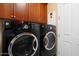Laundry room with black front load washer and dryer next to a door at 20369 N 272Nd Ave, Buckeye, AZ 85396