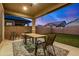 Covered patio with table, chairs, and decorative rug, overlooking a well-maintained backyard with artificial turf at 22922 E Mayberry Rd, Queen Creek, AZ 85142