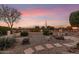 Landscaped backyard with fire pit, stone pathway, and desert plants at sunset at 23187 W Lasso Ln, Buckeye, AZ 85326