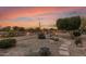 Landscaped backyard with fire pit, stone pathway, and desert plants at sunset at 23187 W Lasso Ln, Buckeye, AZ 85326