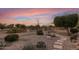 Landscaped backyard with fire pit, stone pathway, and desert plants at sunset at 23187 W Lasso Ln, Buckeye, AZ 85326