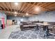 Unfinished basement featuring exposed wood ceiling, concrete flooring, and a comfortable sitting area with a large sofa at 9120 E Dennis St, Mesa, AZ 85207