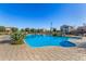 Community pool with a bright blue water, safety handrails, chairs, and lush green landscaping at 1094 S 151St S Ln, Goodyear, AZ 85338