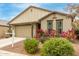 Single story home with beige exterior, red flowers, and a two-car garage at 1094 S 151St S Ln, Goodyear, AZ 85338