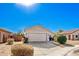 Tan house with a two-car garage, landscaping, and a sunny day at 15365 W Caribbean Ln, Surprise, AZ 85379