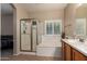 Bright bathroom featuring a glass shower and tub, complemented by a light-filled window at 163 W Dragon Tree Ave, Queen Creek, AZ 85140