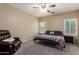 Comfortable bedroom with a cozy reading chair, ceiling fan, and bright windows at 163 W Dragon Tree Ave, Queen Creek, AZ 85140