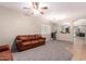 Open living room features neutral walls, a ceiling fan, and a comfortable leather sofa at 163 W Dragon Tree Ave, Queen Creek, AZ 85140