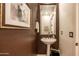 Elegant powder room with pedestal sink and dark brown walls at 19334 W Pasadena Ave, Litchfield Park, AZ 85340