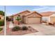 Tan house with a two-car garage, landscaping, and a paved driveway at 2023 E Glenhaven Dr, Phoenix, AZ 85048