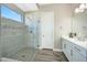 Bathroom featuring walk-in shower with glass door, stone tiling, and a modern single sink vanity at 20641 W Medlock Dr, Buckeye, AZ 85396