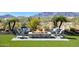 An outdoor fire pit with chairs surrounded by professionally landscaped desert flora and picturesque mountains at 20641 W Medlock Dr, Buckeye, AZ 85396