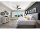 Spacious main bedroom with wood flooring, large windows, and a tray ceiling with modern ceiling fan at 20641 W Medlock Dr, Buckeye, AZ 85396