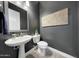 Modern powder room with a pedestal sink, toilet, and dark painted walls at 20641 W Medlock Dr, Buckeye, AZ 85396