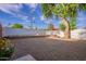 Spacious backyard featuring gravel, a brick retaining wall, mature tree, and a white perimeter wall at 3002 E Mitchell Dr, Phoenix, AZ 85016