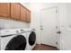 This laundry room features cabinetry above the washer and dryer, tile floors and a white door at 18906 E Cattle Dr, Queen Creek, AZ 85142