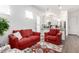 Comfortable living room with two red sofas, arm chair, and open access to the kitchen at 21716 E Waverly Dr, Queen Creek, AZ 85142