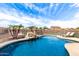 Inviting in-ground pool with rock waterfall feature, lounge chairs, and safety fence under a sunny, partly cloudy sky at 32504 N Cherry Creek Rd, San Tan Valley, AZ 85144