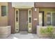 Front entrance of townhome with modern brown door and landscaping at 6605 N 93Rd Ave # 1087, Glendale, AZ 85305