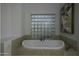 Relaxing bathroom with a large soaking tub and glass block window at 10040 N 78Th Pl, Scottsdale, AZ 85258