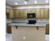 Bright kitchen features wood cabinetry, an eat-in island, tile floors, and sleek black appliances at 2335 W Muirfield Dr, Anthem, AZ 85086