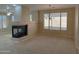 Comfortable living room featuring a cozy fireplace, large windows, neutral paint, and carpet flooring at 2335 W Muirfield Dr, Anthem, AZ 85086