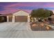 Front view of a tan house with a brown garage door and landscaped yard at 27062 W Behrend Dr, Buckeye, AZ 85396