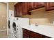Bright laundry room with a utility sink and cabinets at 27062 W Behrend Dr, Buckeye, AZ 85396