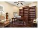Home office features hardwood floors, built-in shelves, and a large desk at 27062 W Behrend Dr, Buckeye, AZ 85396