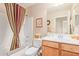 Guest bathroom with tub, shower, and wood vanity at 37110 W Leonessa Ave, Maricopa, AZ 85138